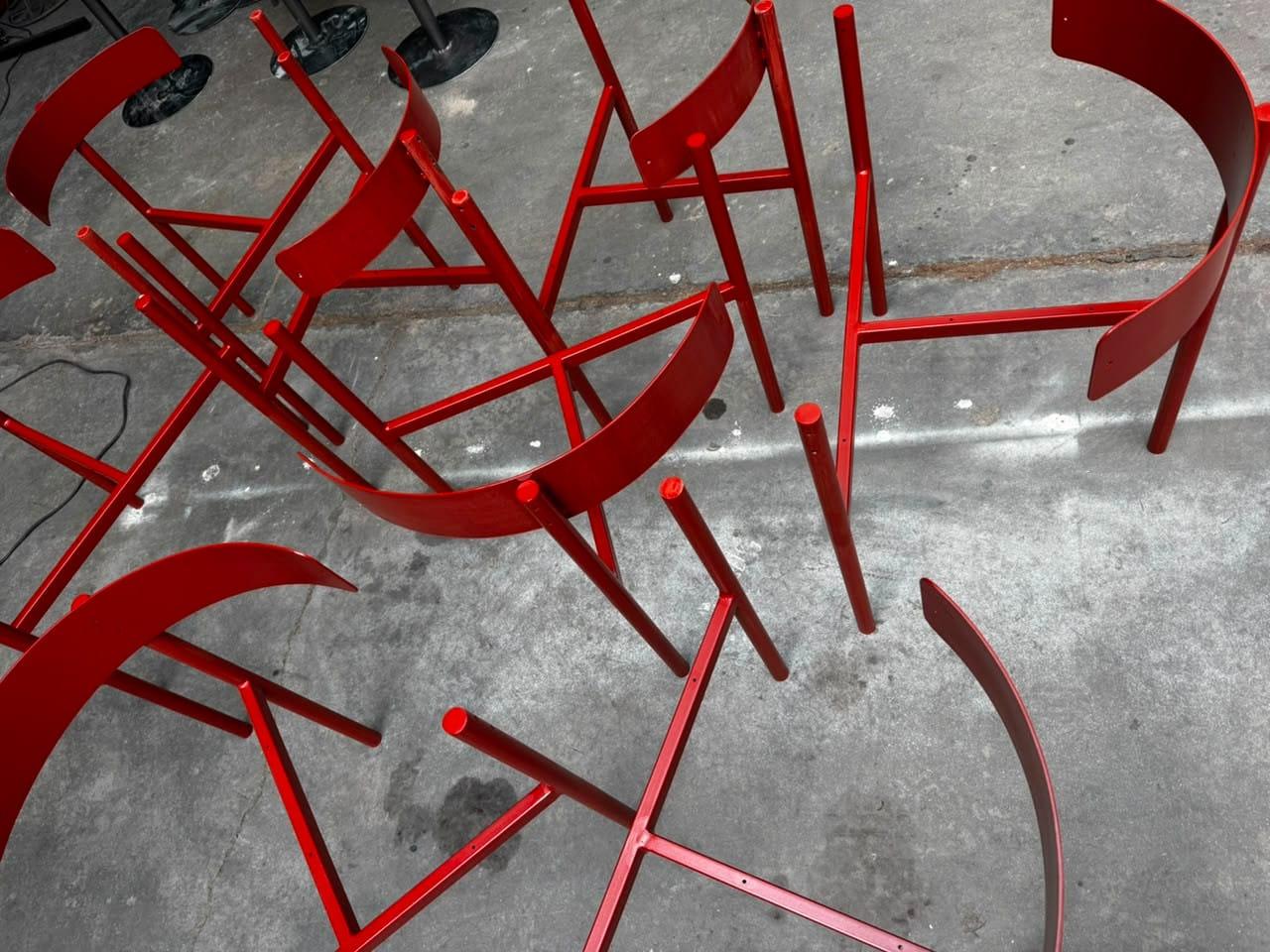 Estructuras de sillas de hierro pintadas en rojo, apiladas en la fábrica