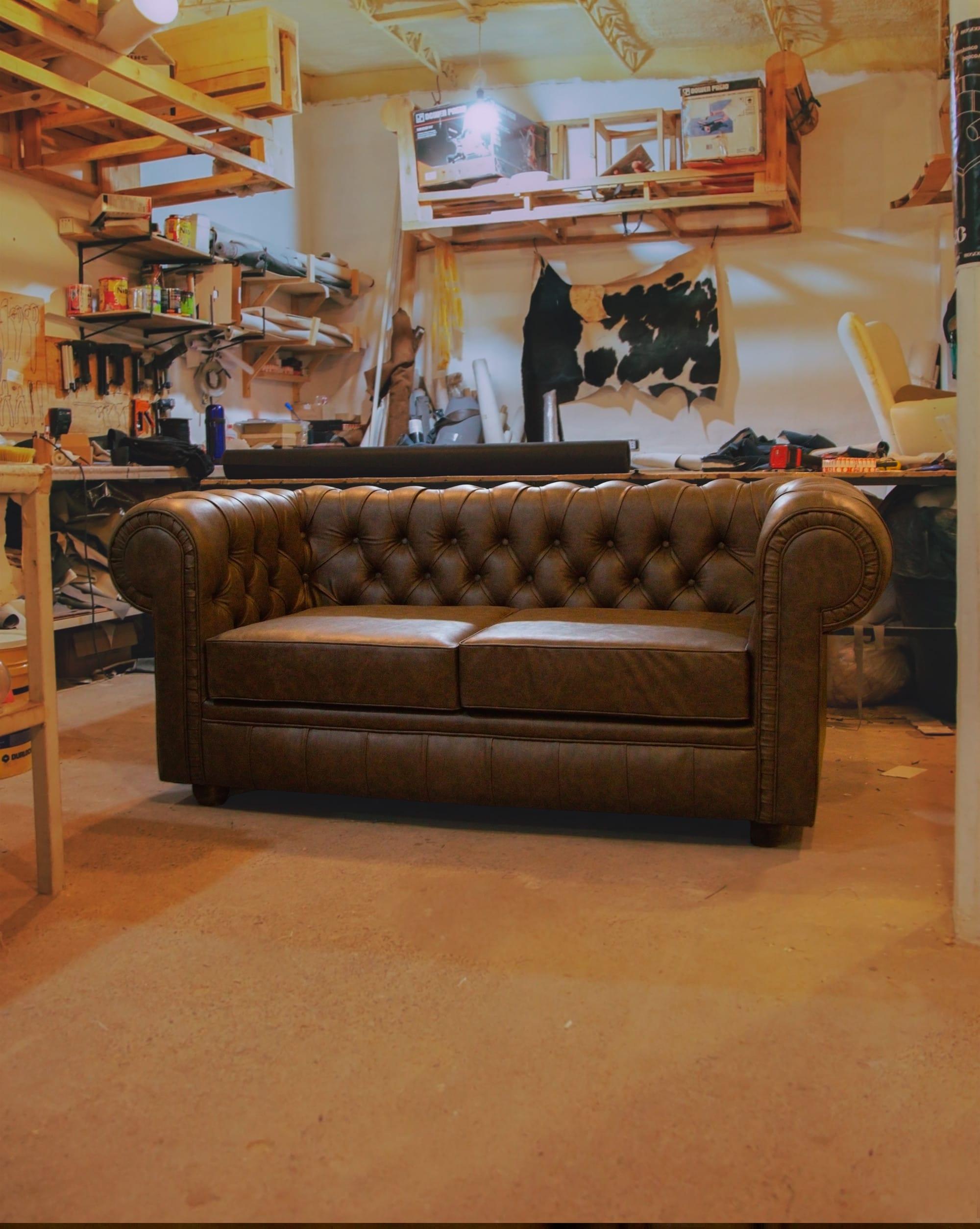 Sillón Chesterfield terminado dentro del taller, entre herramientas y cueros