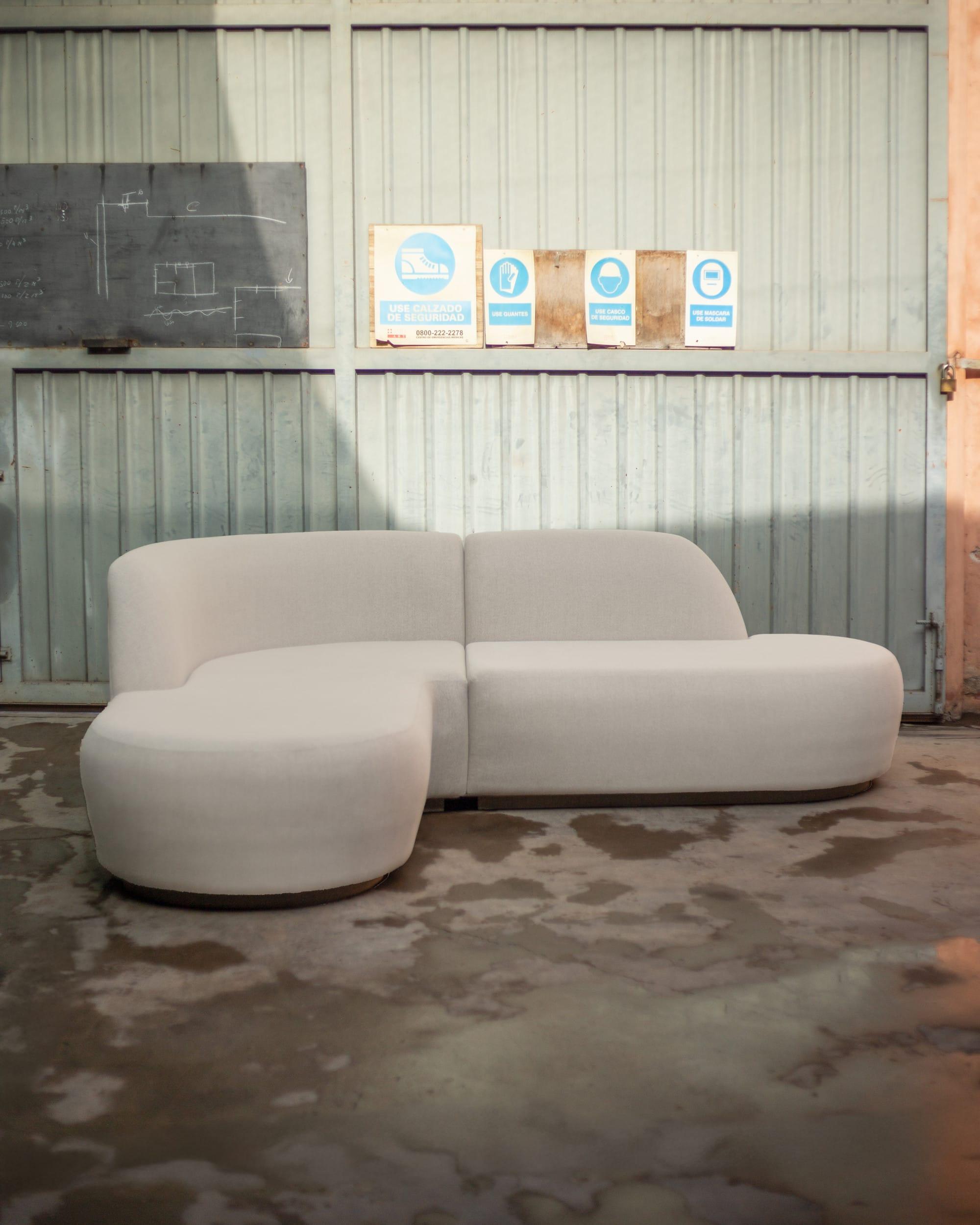 Sillón Guillermo, modular de silueta curva tapizado en género claro, en el patio de la fábrica